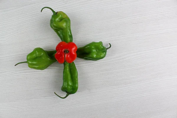 Small red and green peppers on white background