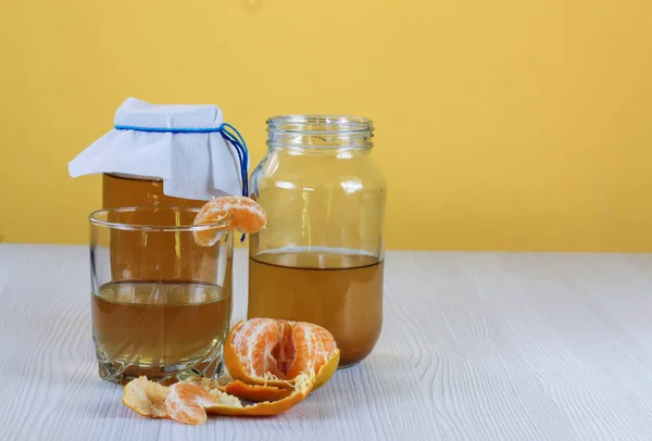 fermented drink, jun tea healthy natural probiotic in a glass jar, with a glass and tangerine ready to drink