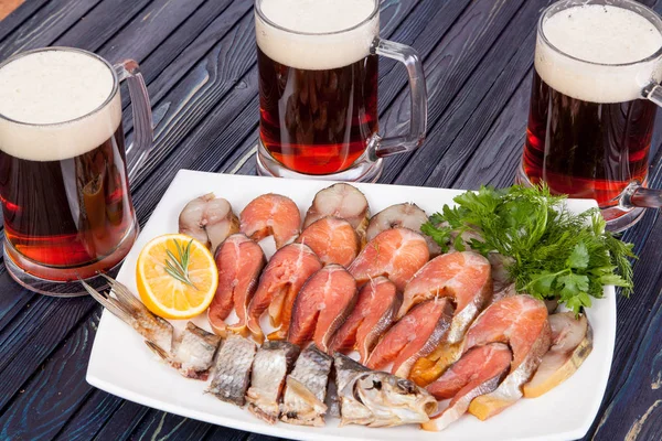 appetizer for beer from dried fish, cheese sticks, smoked onion cheese and loafs with beer on the table for use in design