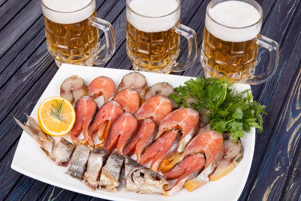 appetizer for beer from dried fish, cheese sticks, smoked onion cheese and loafs with beer on the table for use in design