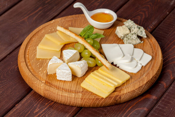 delicious cheese plate or cheese platter from several types of cheese with honey and fruit for creative work in cooking