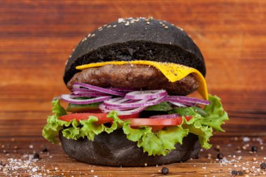 Fast food, iştah açıcı siyah hamburger, güzel ahşap zemin, mutfak tasarımı için ortaya konulan