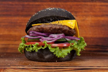 Fast food, iştah açıcı siyah hamburger, güzel ahşap zemin, mutfak tasarımı için ortaya konulan