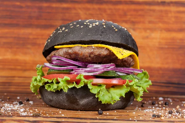 Fast food, appetizing black burger, beautifully laid out on a wooden background, for culinary design
