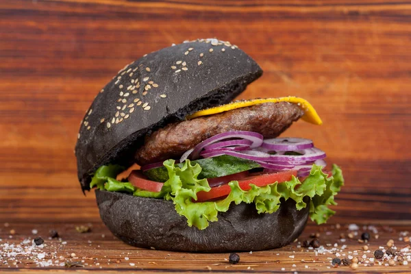 Fast food, appetizing black burger, beautifully laid out on a wooden background, for culinary design
