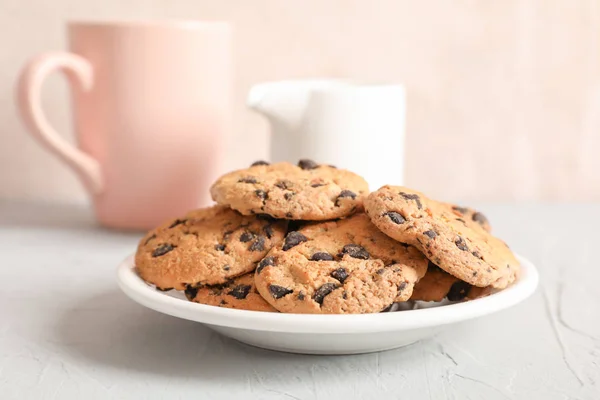 Teller Mit Leckeren Schokoladenkeksen Und Verschwommener Tasse Milch Auf Grauem — Stockfoto