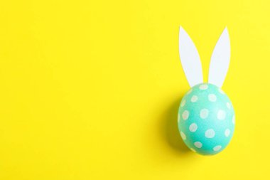 Paskalya yortusu yumurta sarı arka plan üzerinde sevimli tavşan kulakları ile dekore edilmiştir. Metin için yer