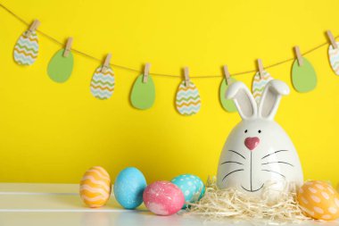 Bunny ve Paskalya yumurtaları renk arka plan karşı masada dekore edilmiş