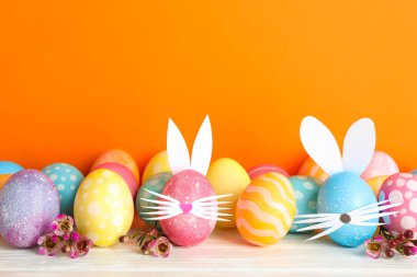 Paskalya yumurtaları ve sevimli tavşan'ın kulakları renk arka plan karşı masada dekore edilmiştir. Metin için yer