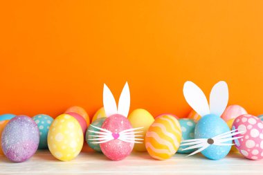 Paskalya yumurtaları ve sevimli tavşan'ın kulakları renk arka plan karşı masada dekore edilmiştir. Metin için yer