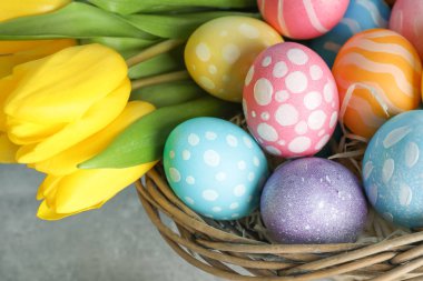 Paskalya sepeti renkli yumurta ve ahşap arka plan üzerinde çiçek dolu. Yakın çekim