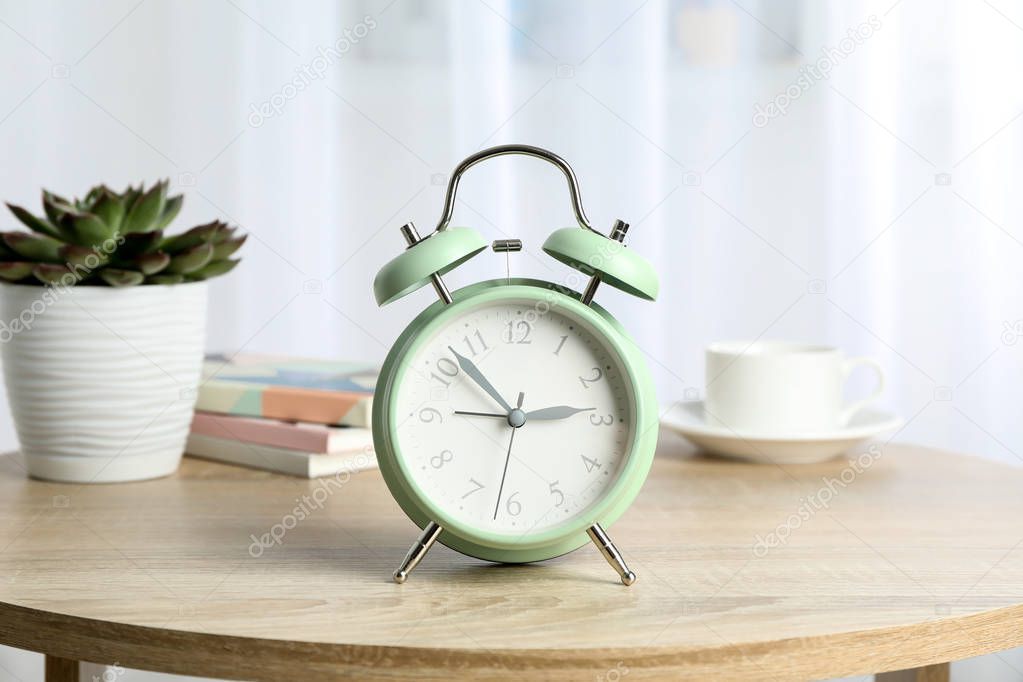 Beautiful retro alarm clock with cup of coffee, succulent plant 
