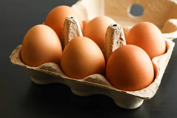 Huevos de pollo en caja de cartón sobre fondo negro, espacio para texto — Foto de Stock