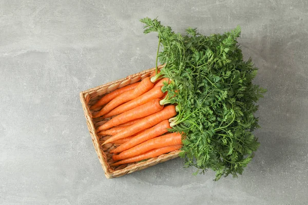 Плетеная корзина с созревшей морковкой на сером столе, место для текста — стоковое фото