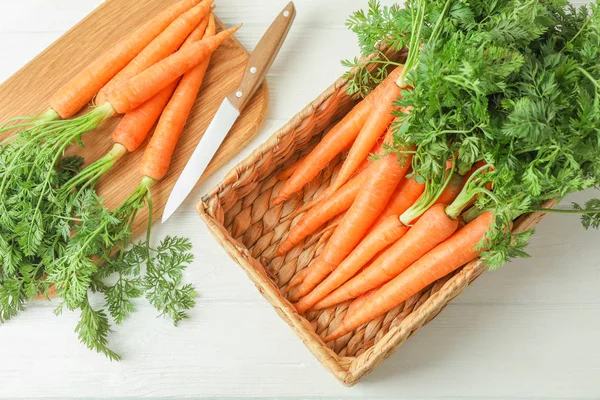 Доска для резки спелой морковки и ножа на деревянном столе — стоковое фото