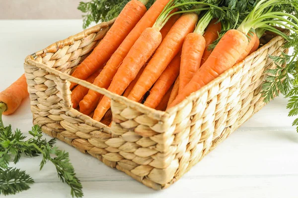 Плетеная корзина с созревшей морковью на деревянном столе, крупным планом — стоковое фото