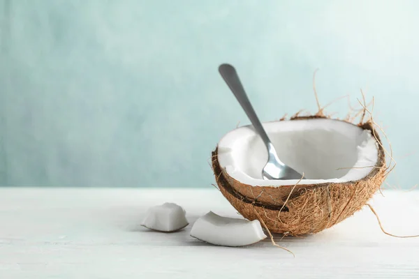 Halve kokosnoot met lepel op houten tafel tegen de grijze achtergrond — Stockfoto