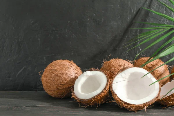 Cocos con rama de palma sobre mesa de madera contra fondo negro — Foto de Stock