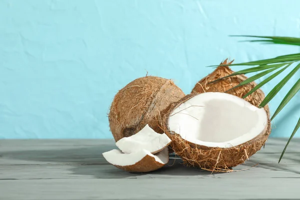 Cocos com ramo de palma na mesa de madeira contra backgrou cor — Fotografia de Stock