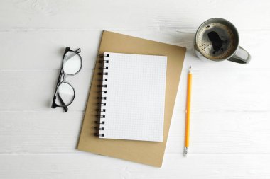 Copybooks, fincan kahve, kalemler ve ahşap backgrou gözlük