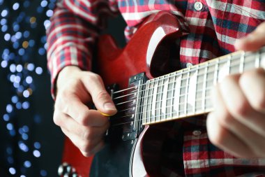 Adam karanlık arka plana karşı elektrik gitar oynarken, çekim