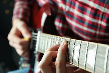 Adam karanlık arka plana karşı elektrik gitar oynarken, çekim