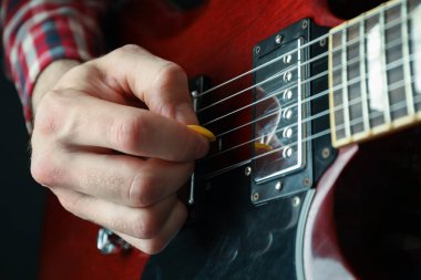 Adam karanlık arka plana karşı elektrik gitar oynarken, çekim