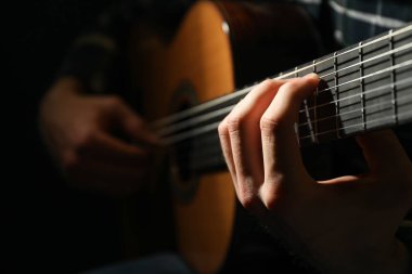 Adam karanlık arka plana karşı klasik gitar oynarken, çekim