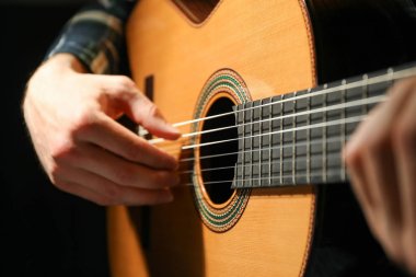 Adam karanlık arka plana karşı klasik gitar oynarken, çekim