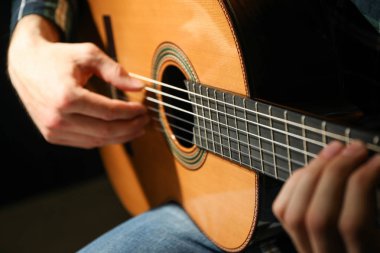 Adam karanlık arka plana karşı klasik gitar oynarken, çekim