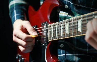 Adam karanlık arka plana karşı elektrik gitar oynarken, çekim