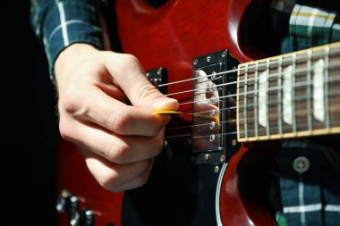 Adam karanlık arka plana karşı elektrik gitar oynarken, çekim