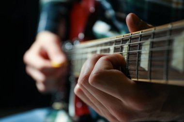 Adam karanlık arka plana karşı elektrik gitar oynarken, çekim