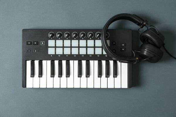 Midi keyboard with headphones on dark background, space for text