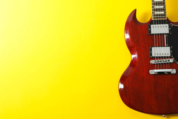 Beautiful electric guitar on yellow background, space for text