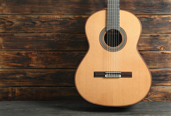 Beautiful six - string classic guitar against wooden background,