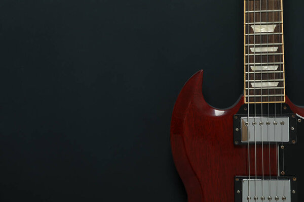 Beautiful six - string electric guitar on dark background, space for text
