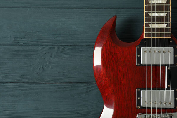 Beautiful six - string electric guitar on wooden background, space for text