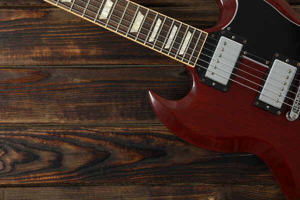 Beautiful six - string electric guitar on wooden background, space for text