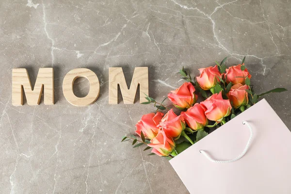 Geschenktüte mit einem Strauß orangefarbener Rosen und der Aufschrift Mom on bro — Stockfoto