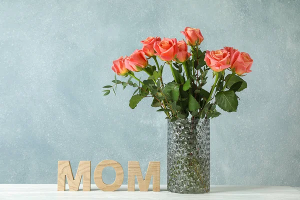 Vaso com rosas alaranjadas e inscrição Mãe na mesa branca agains — Fotografia de Stock