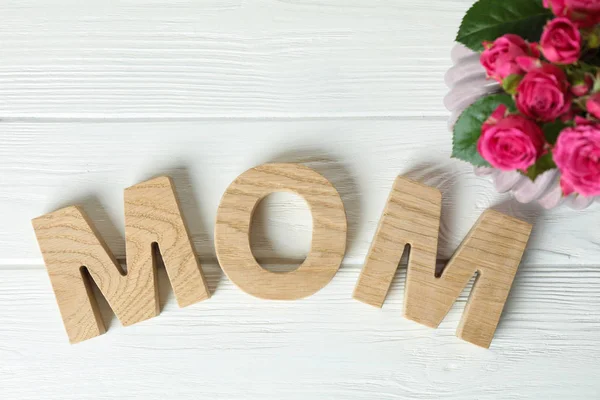 Samenstelling met inscriptie moeder en roze rozen op witte houten — Stockfoto