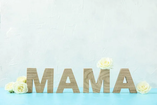 Inskripsi Mom dengan mawar putih di atas meja biru terhadap bac putih — Stok Foto