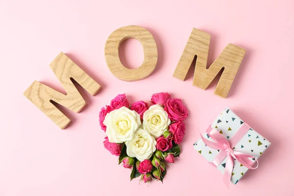 Aufschrift Mutter mit Rosen in Herzform und Geschenk auf Farbe b — Stockfoto
