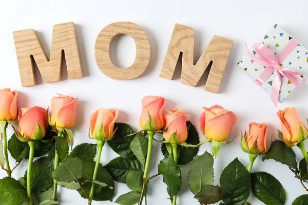 Aufschrift Mutter mit rosa Rosen und Geschenk auf zweifarbigem Hintergrund, — Stockfoto
