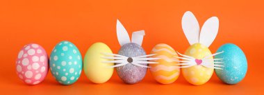 Paskalya yumurtaları ve sevimli tavşan'ın kulakları renk arka plan üzerinde dekore edilmiş