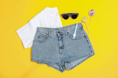 Düz lay kompozisyon: kadın giysi ve aksesuarları, sarı arka plan üzerinde şeker kamışı. Yaz arka planı