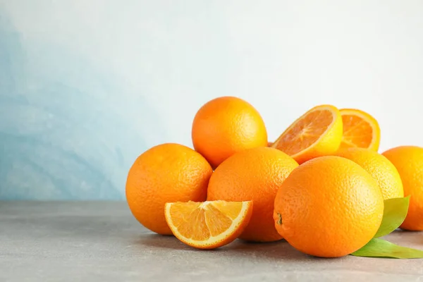 Ώριμα πορτοκάλια με φύλλα σε γκρίζο τραπέζι με ανοιχτόχρωμο φόντο, — Φωτογραφία Αρχείου