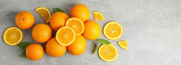 Veel rijpe sinaasappels met bladeren op grijze tafel, bovenaanzicht — Stockfoto