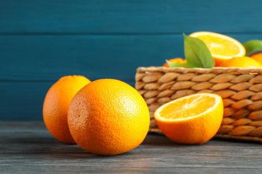 Tahta masada olgun portakallarla dolu hasır sepet, metin için yer.